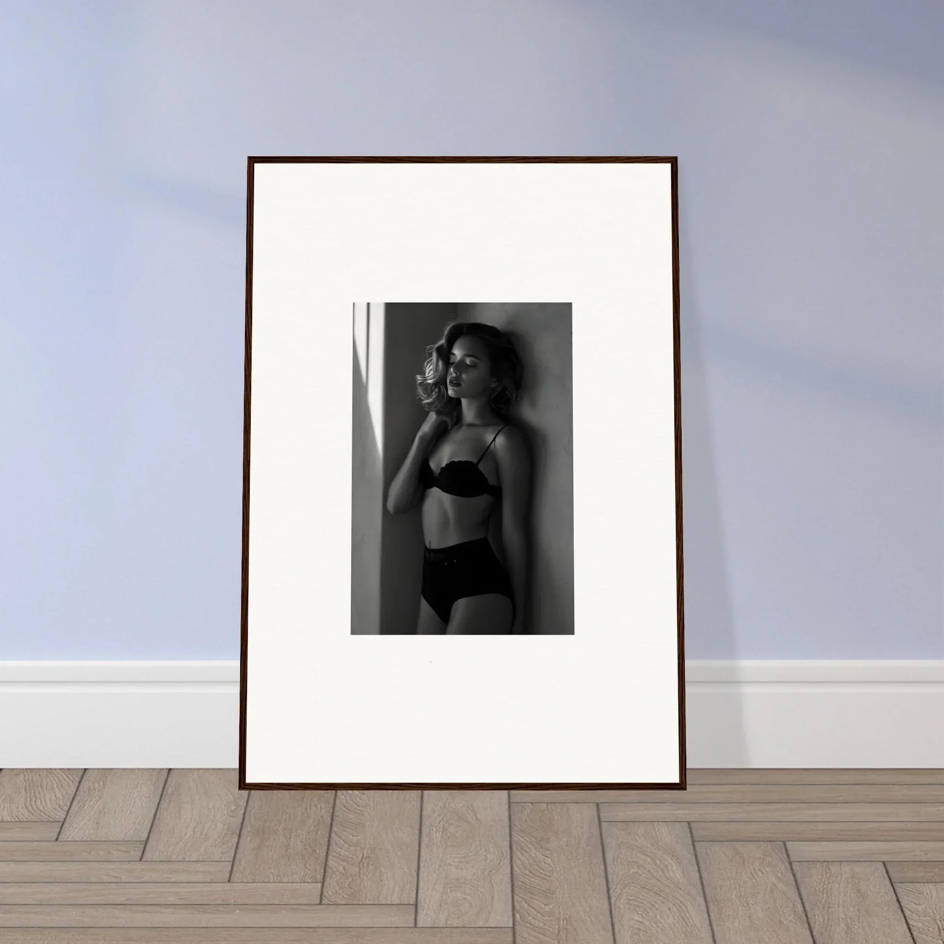 Framed black and white photograph of a woman in lingerie posing against a wall.