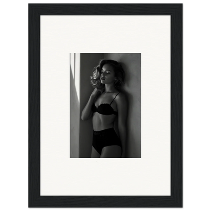 Black and white photograph of a woman in lingerie posing against a wall.