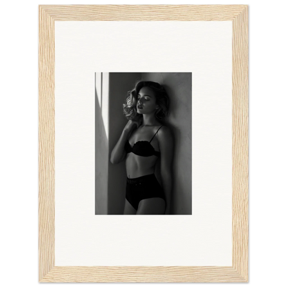 Black and white photograph of a woman in lingerie posing against a wall.