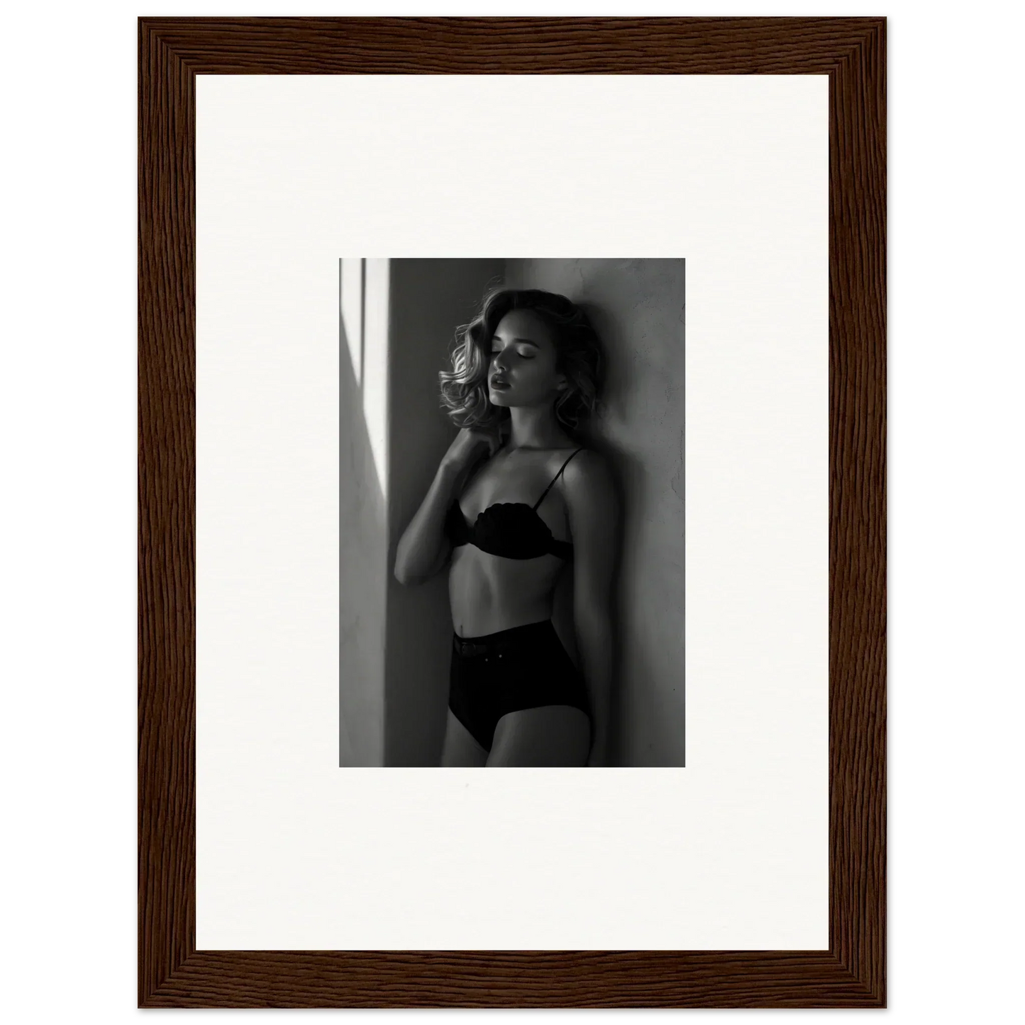 Framed black and white photograph of a woman in lingerie posing against a wall.