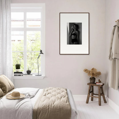 Cozy bedroom with light, neutral decor and a framed black and white photograph on the wall.