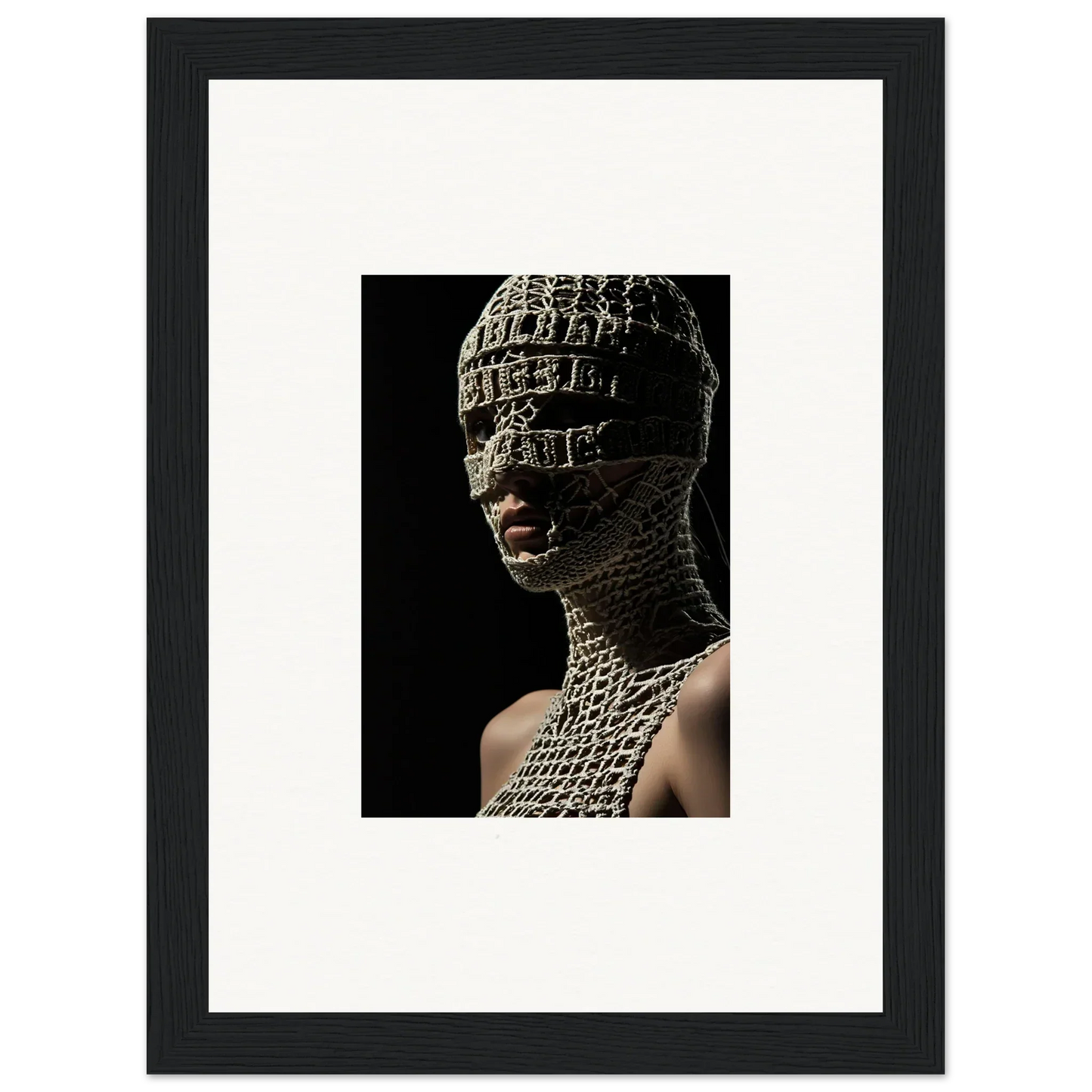 Framed photograph of a person wearing an intricate, textured head covering and neck piece against a dark background.