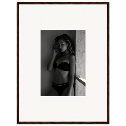 Black and white photograph of a woman in lingerie posing against a wall.