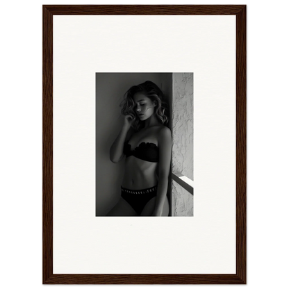 Black and white photograph of a woman in lingerie posing against a wall.