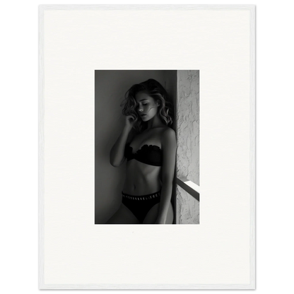 Black and white photograph of a woman in lingerie posing against a wall.