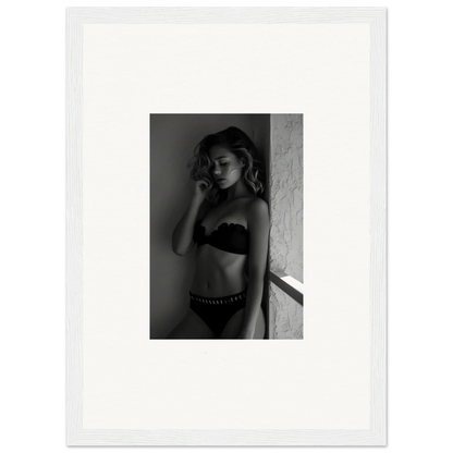 Black and white photograph of a woman in lingerie posing against a wall.