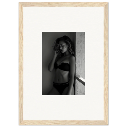 Black and white photograph of a woman in lingerie posed against a wall.