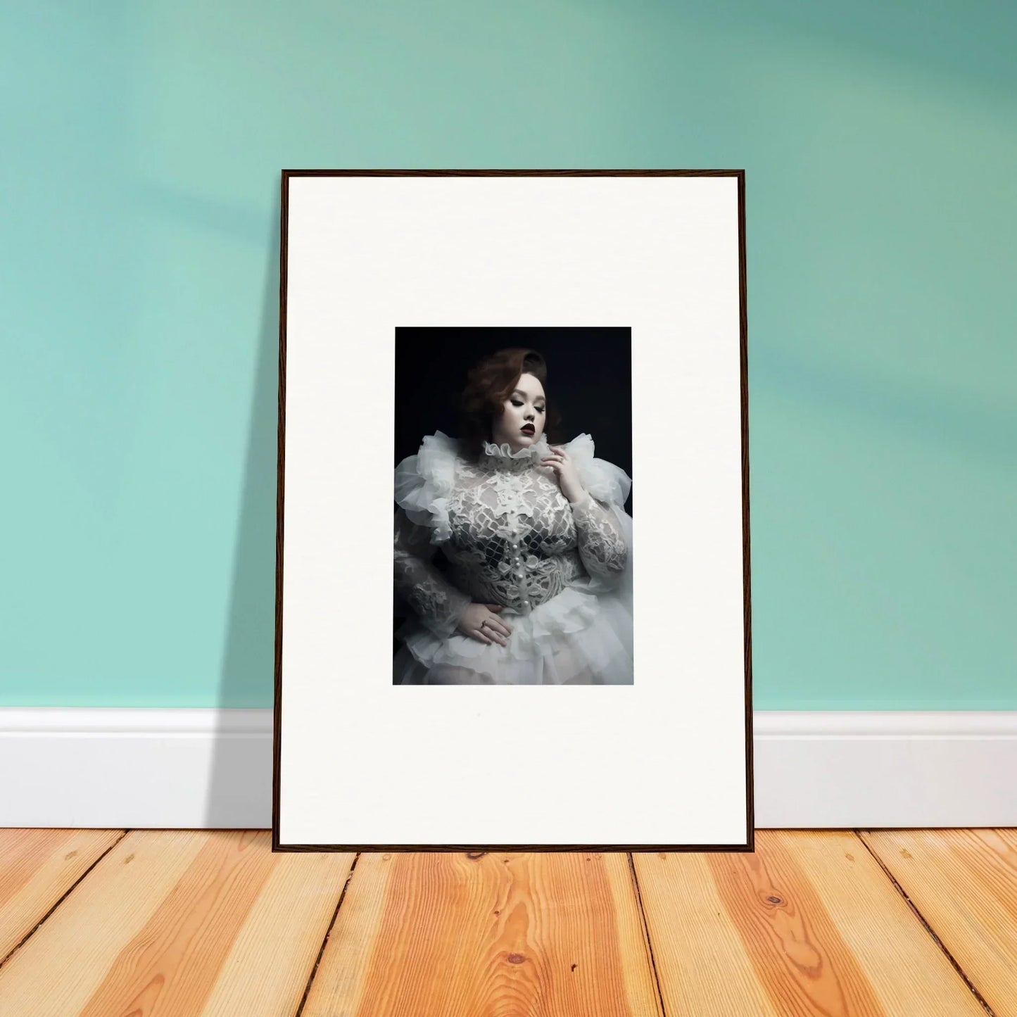 Framed black and white photograph of a person wearing an elaborate white dress with ruffles.