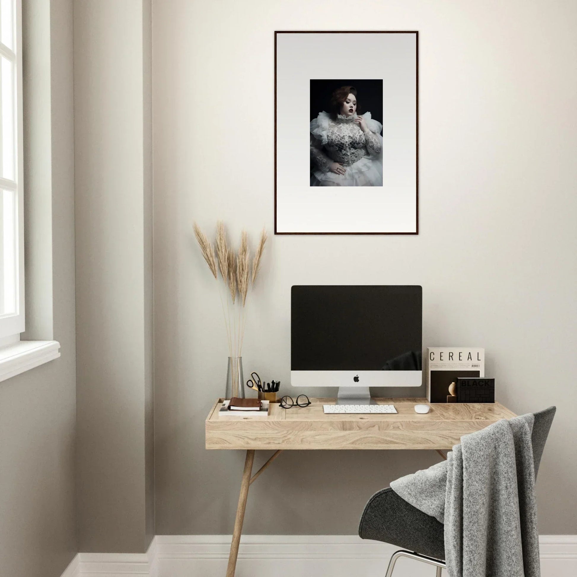 Minimalist home office workspace with a wooden desk, computer, and framed artwork.