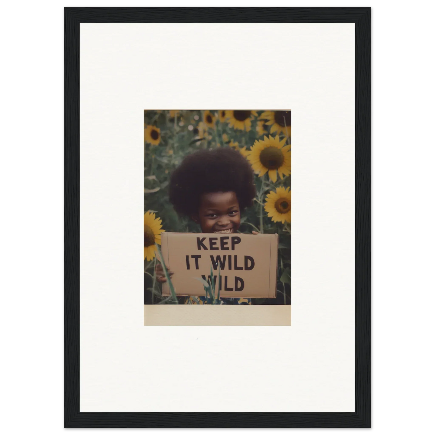 Framed photo of a person with an afro and KEEP IT WILD sign in sunflowers for Euphoric Sun Voyages