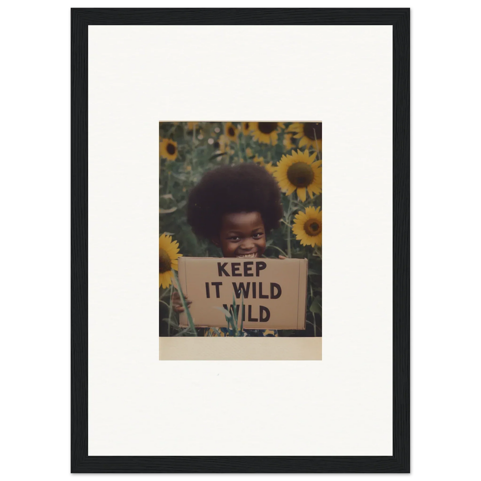 Framed photo of a person with an afro and KEEP IT WILD sign in sunflowers for Euphoric Sun Voyages