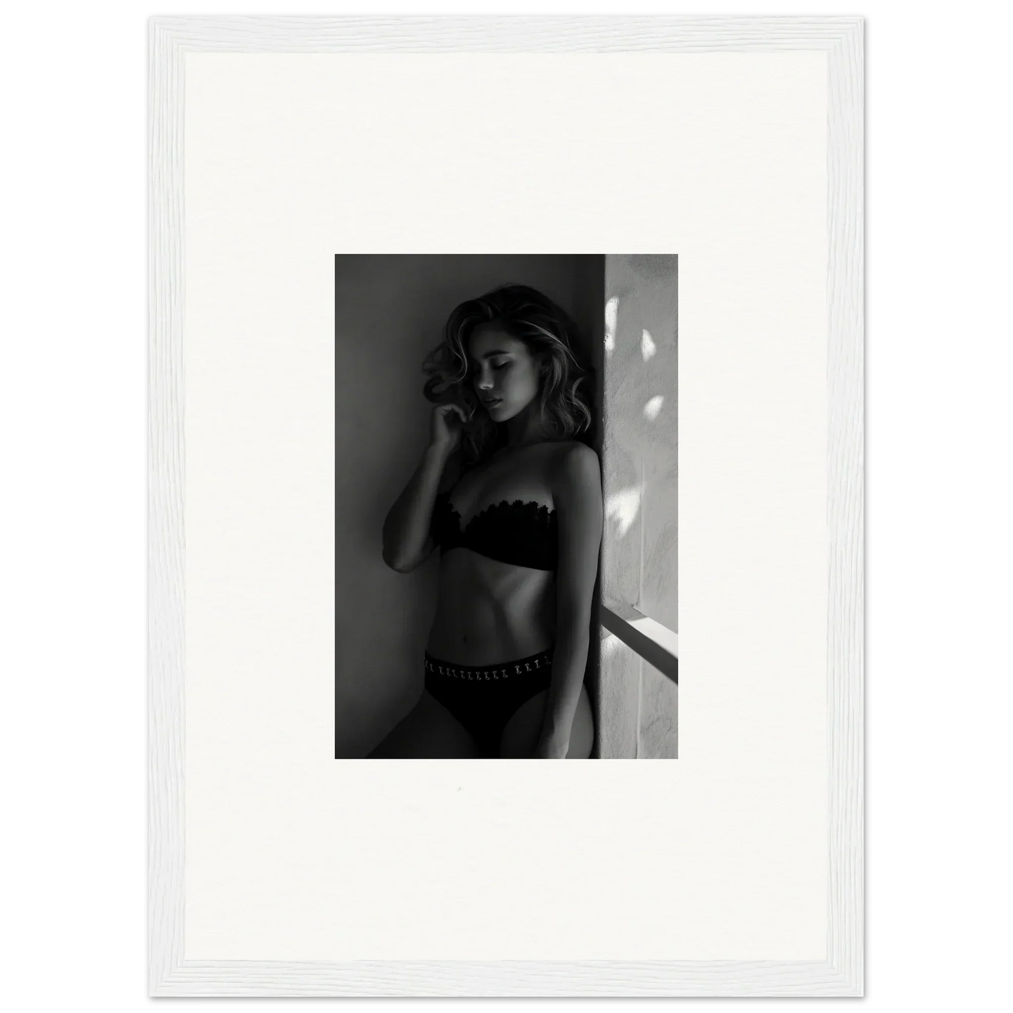 Black and white photograph of a woman in lingerie standing near a window.