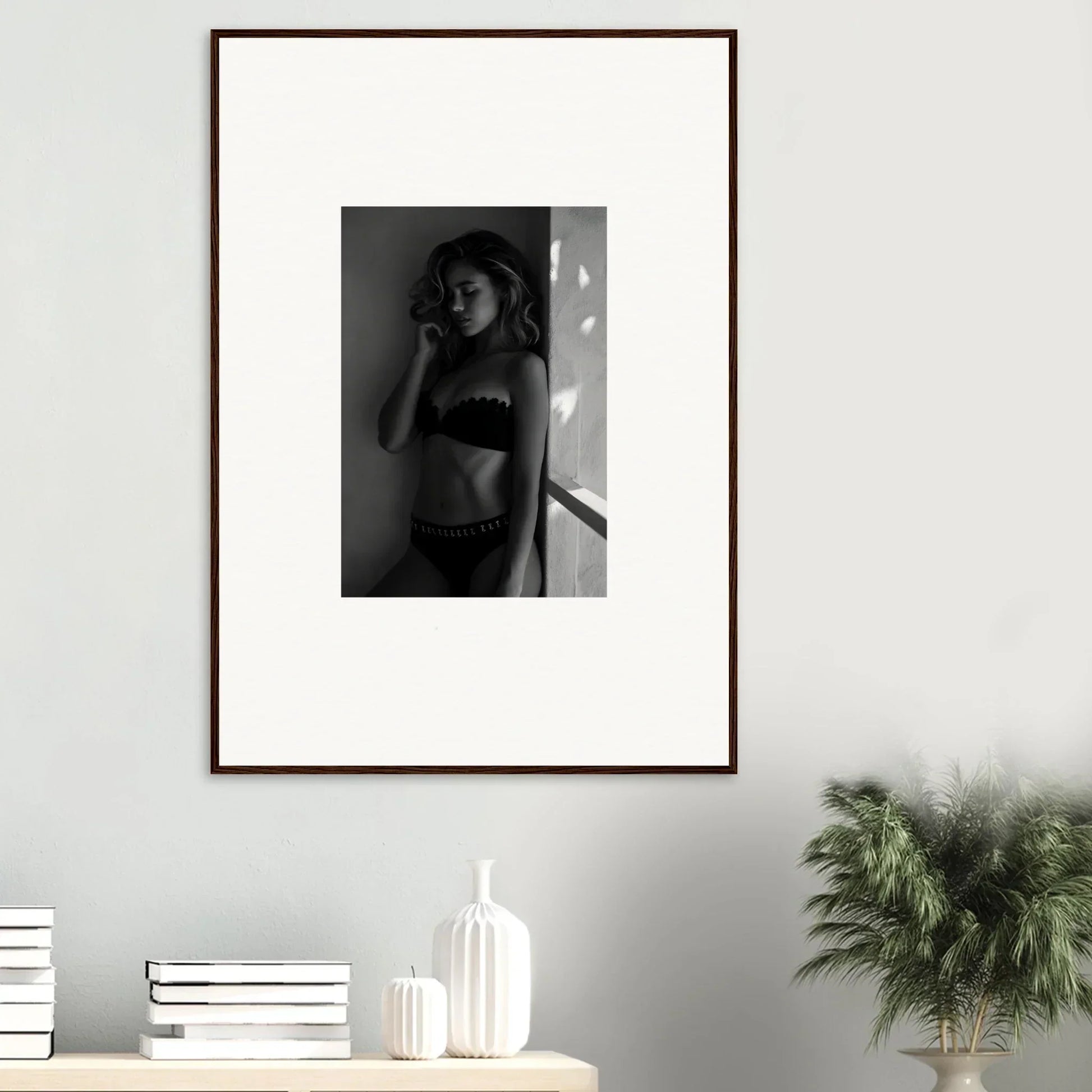 Framed black and white photograph of a woman in lingerie posing against a wall.