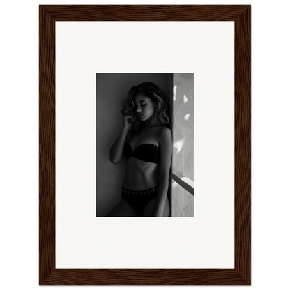 Black and white photograph of a woman in lingerie posed against a wall.