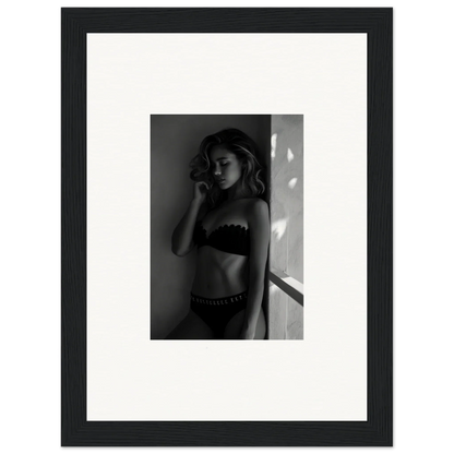 Black and white photograph of a woman in lingerie posing against a wall.