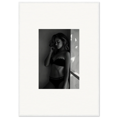 Black and white photograph of a woman in lingerie standing against a wall.