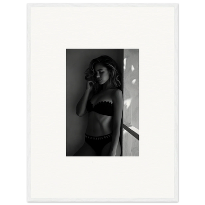 Black and white photograph of a woman in lingerie standing near a wall.