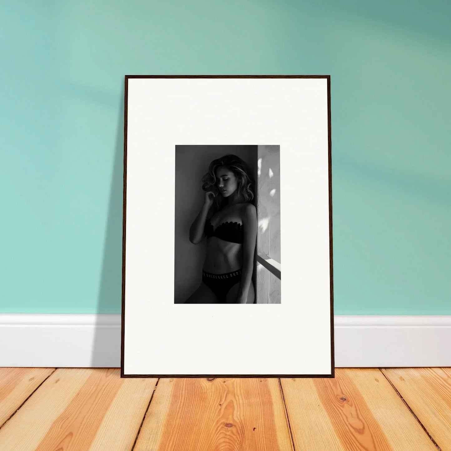 Framed black and white photograph of a person in underwear leaning against a wall.