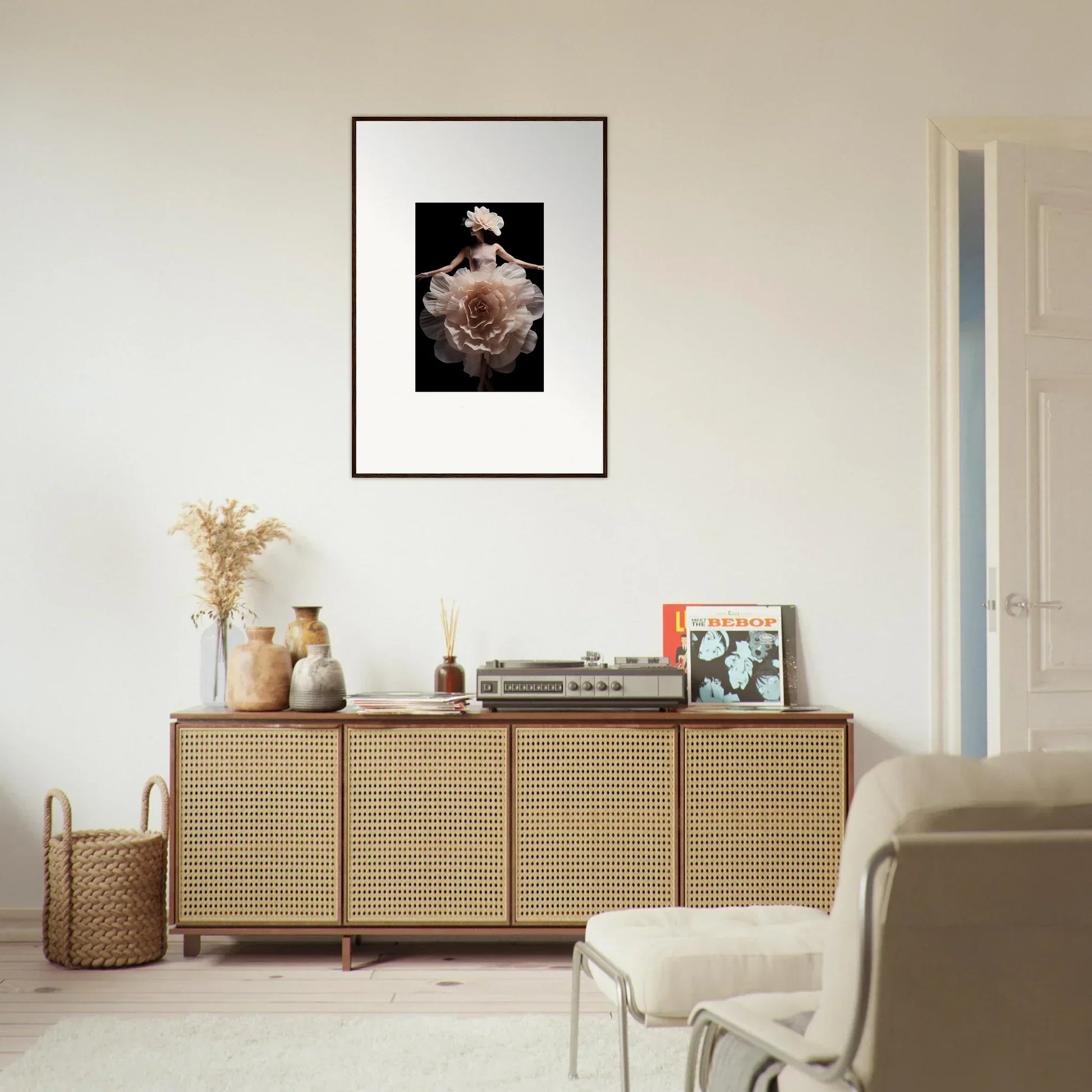 Framed black and white photograph of a figure wearing an ornate headdress, mounted on a white wall.