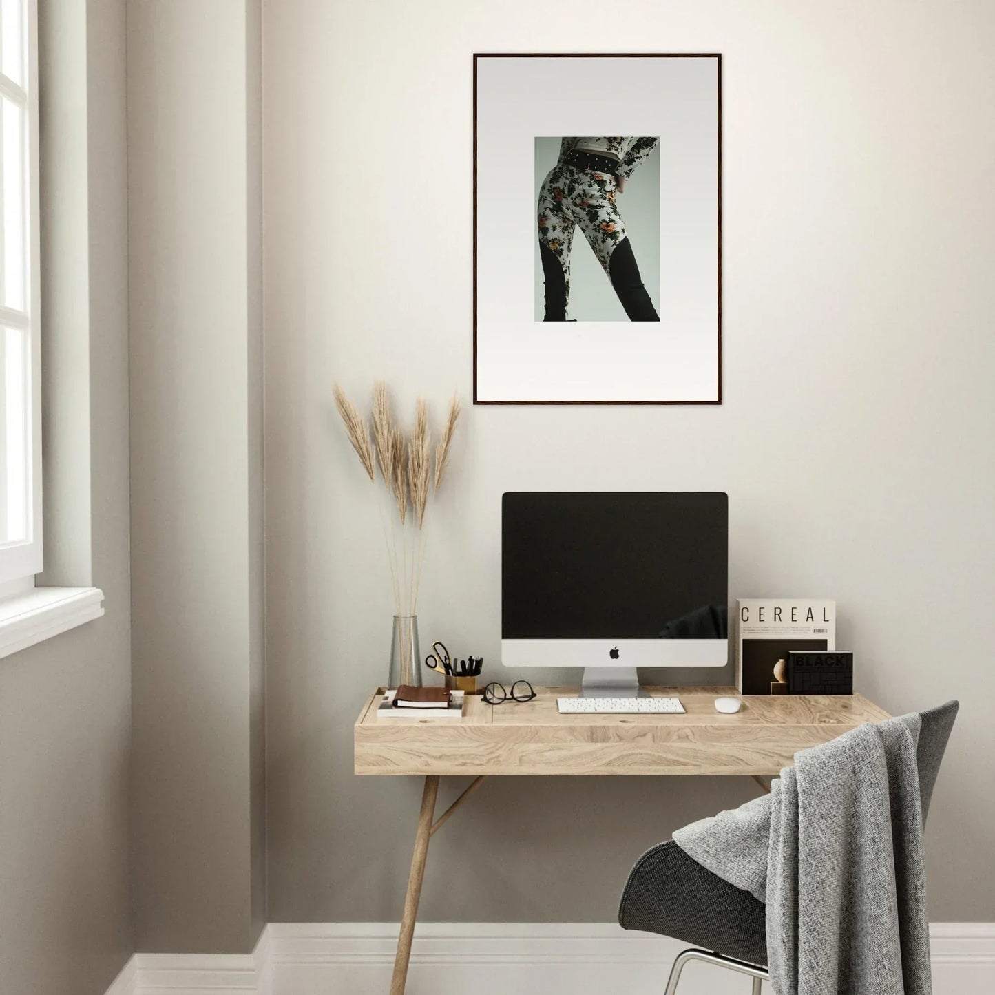 Minimalist home office workspace with a wooden desk, computer, and framed wall art.