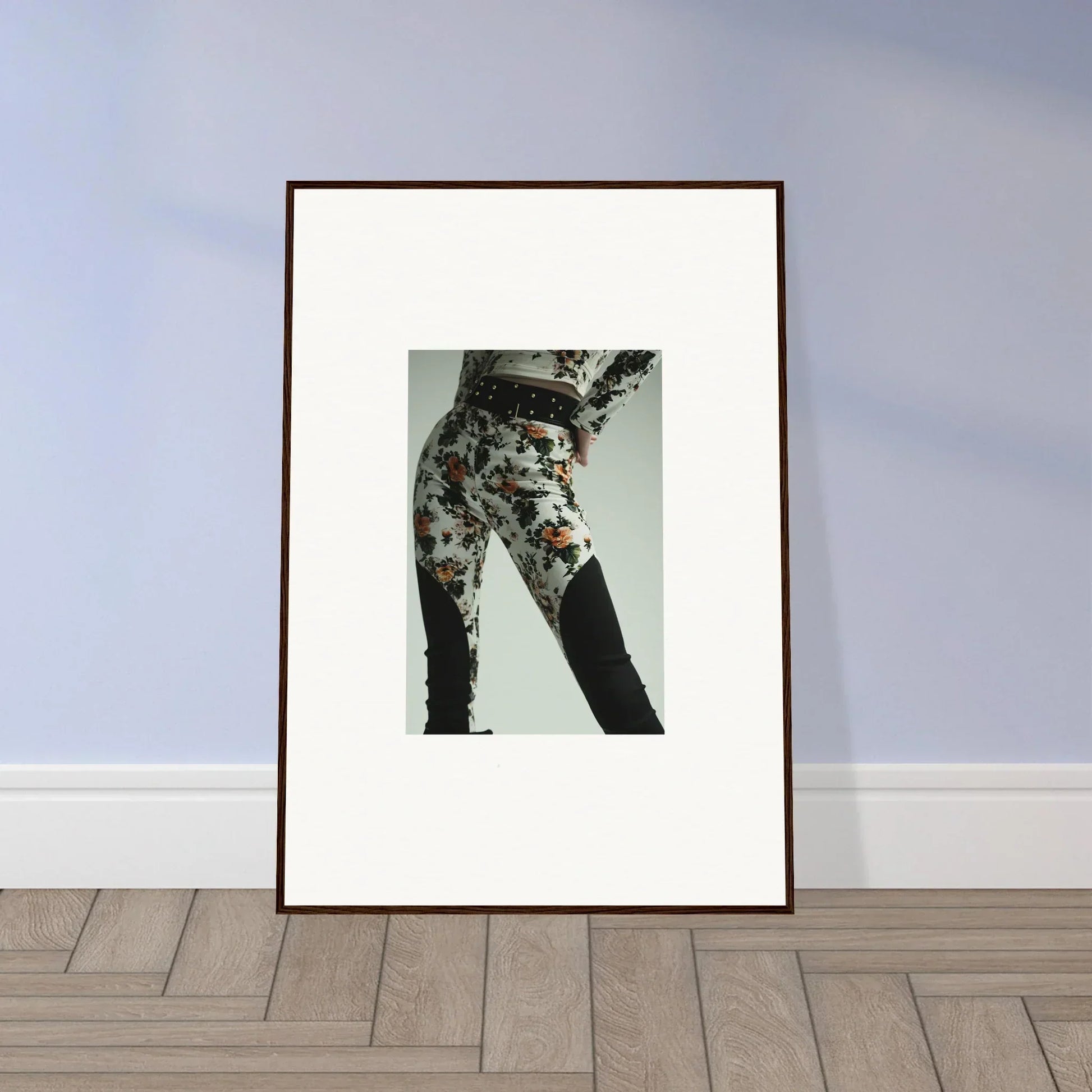 Framed artwork depicting a person’s lower body wearing floral patterned pants.