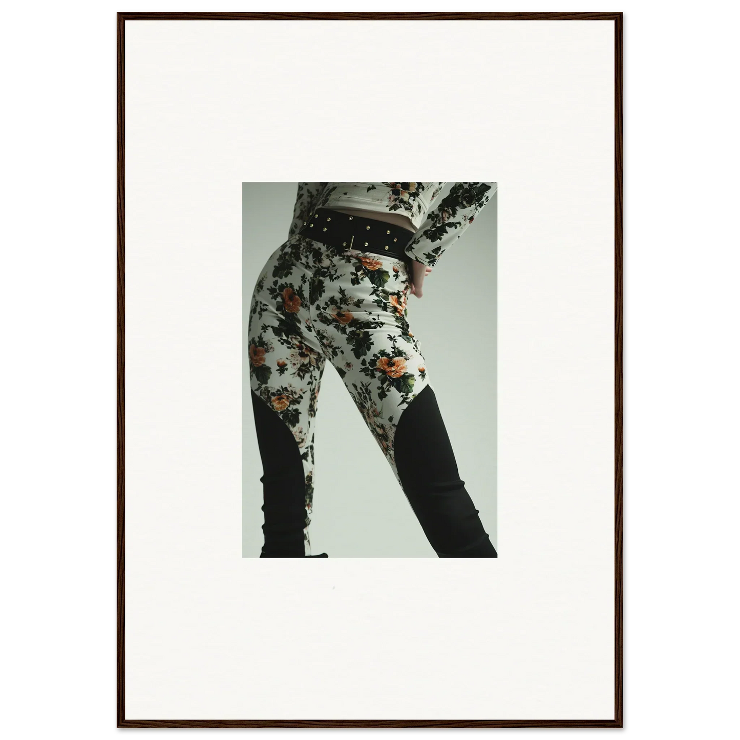 Framed photograph of a person’s lower body wearing floral-patterned pants.