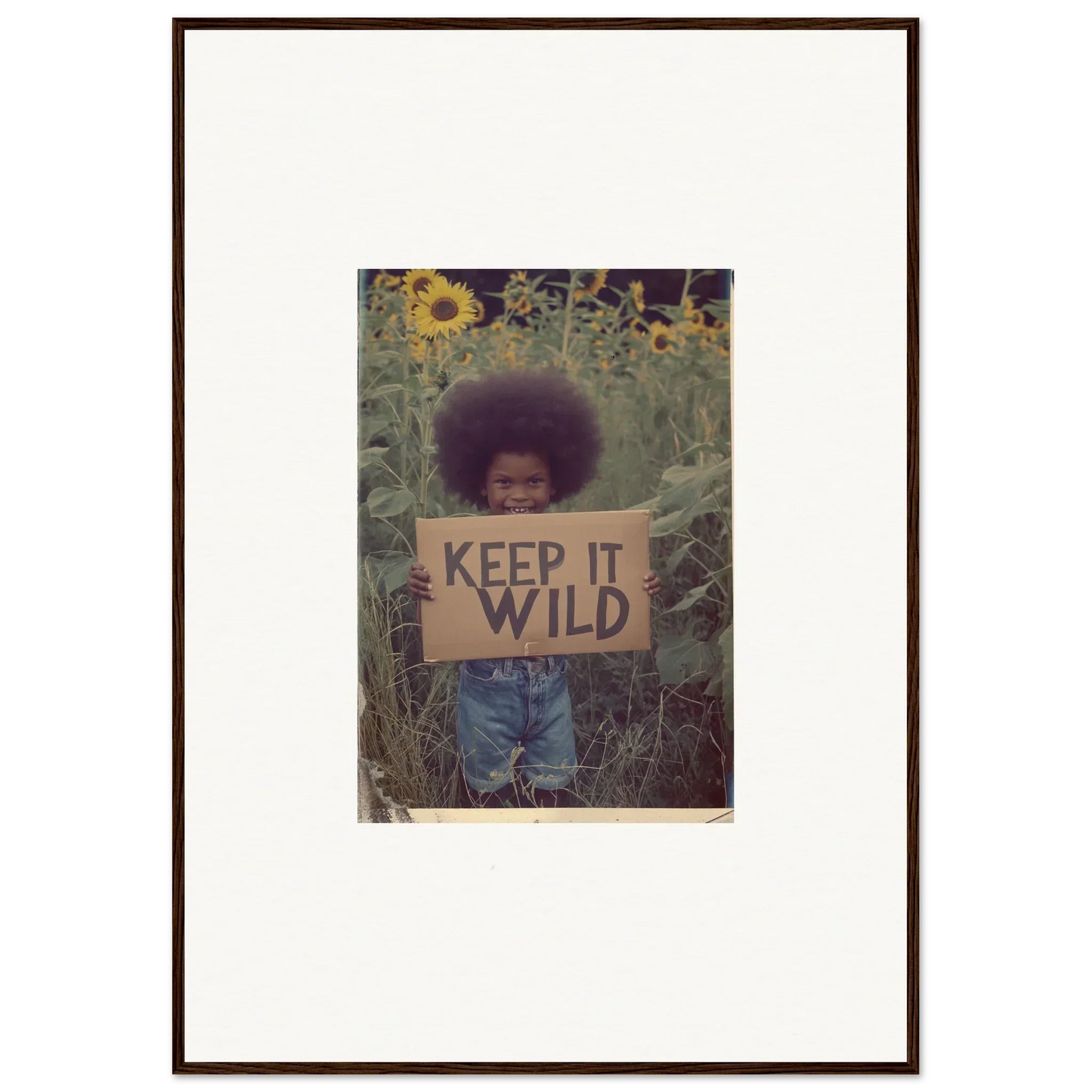 Framed photograph of a person with KEEP IT WILD sign in sunflowers for room decoration