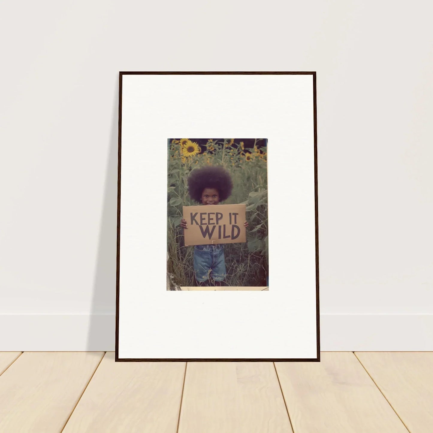 Framed photo of a person with an afro holding a KEEP IT WILD sign for room decoration