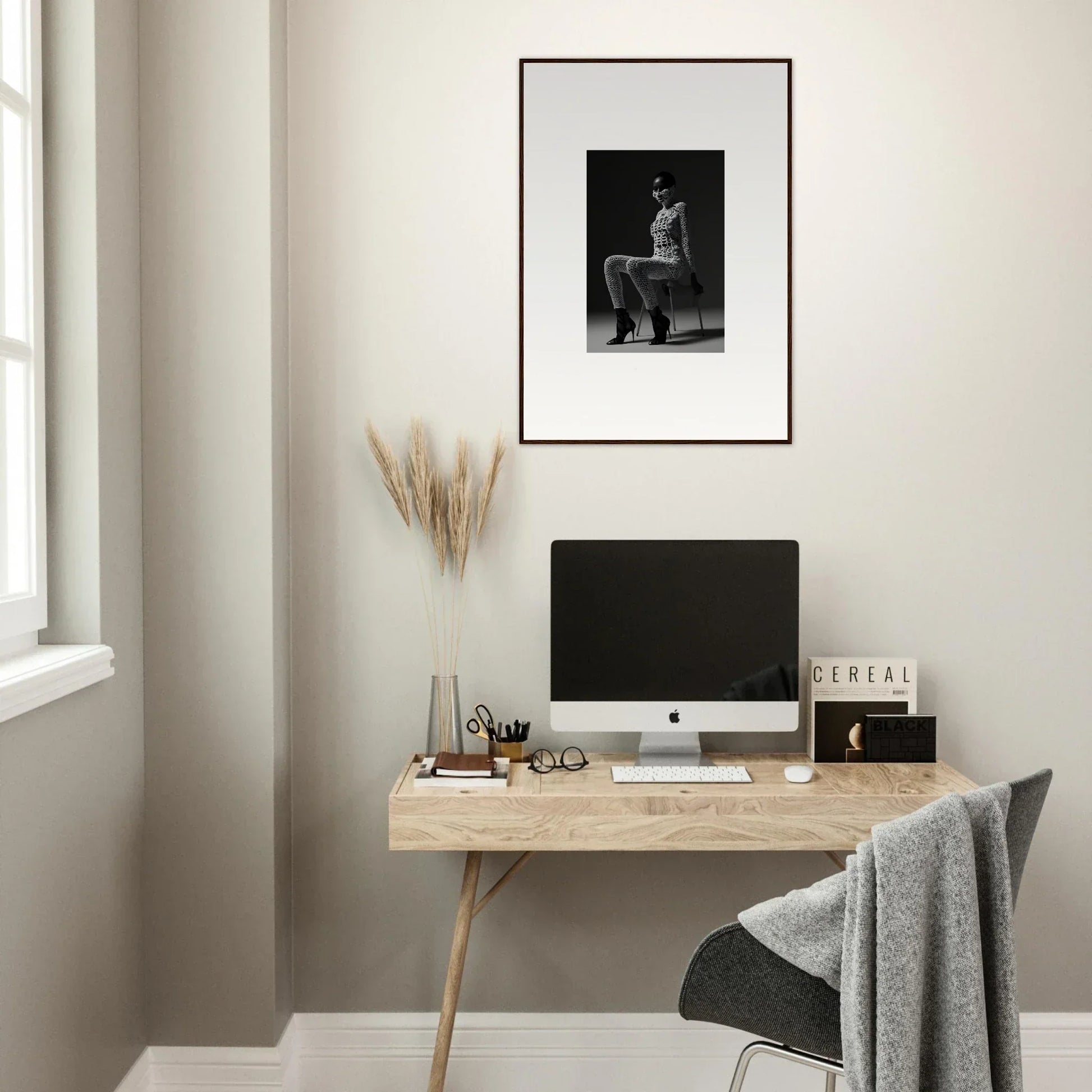 Minimalist wooden desk with a computer monitor and framed artwork above.