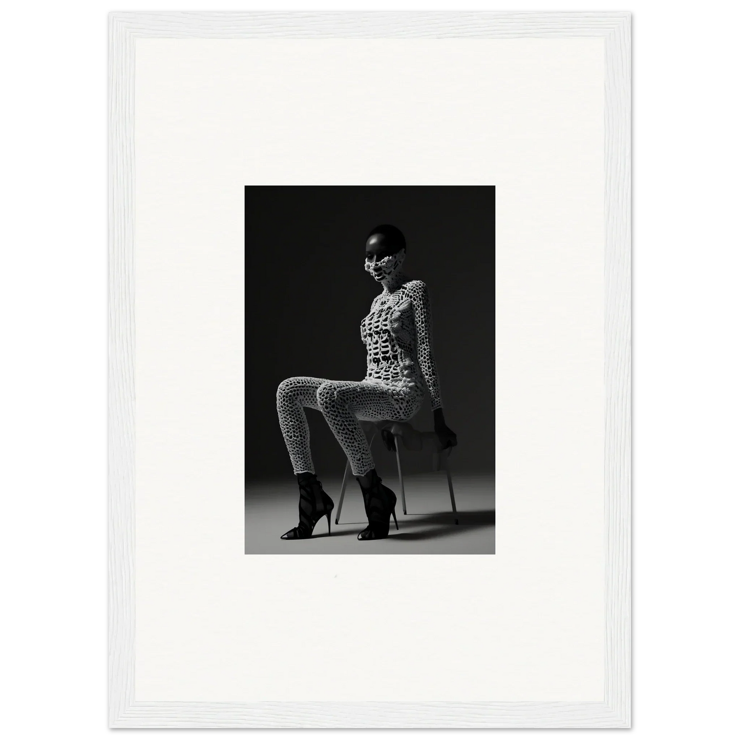 Black and white photograph of a woman seated on a stool wearing a patterned outfit and high heels.