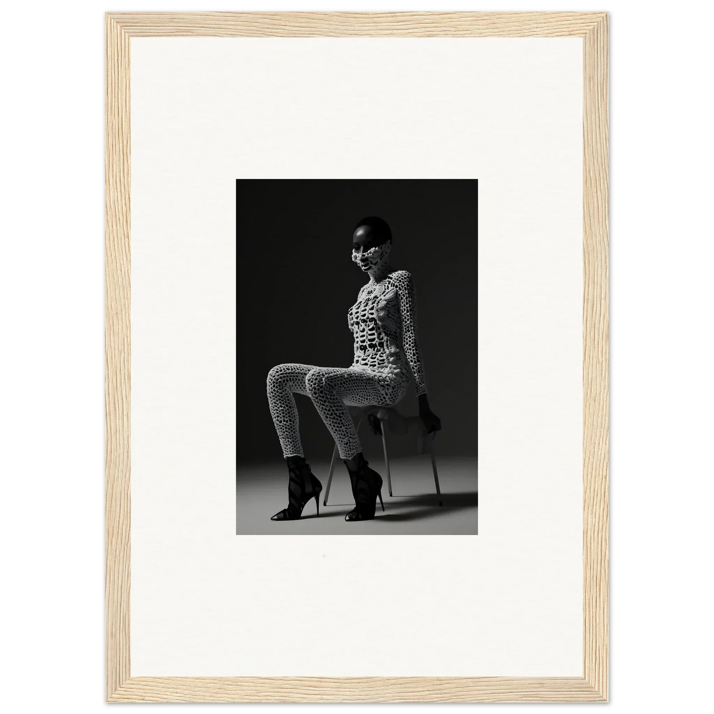 Black and white photograph of a woman in a patterned outfit and high heels posing on a chair.