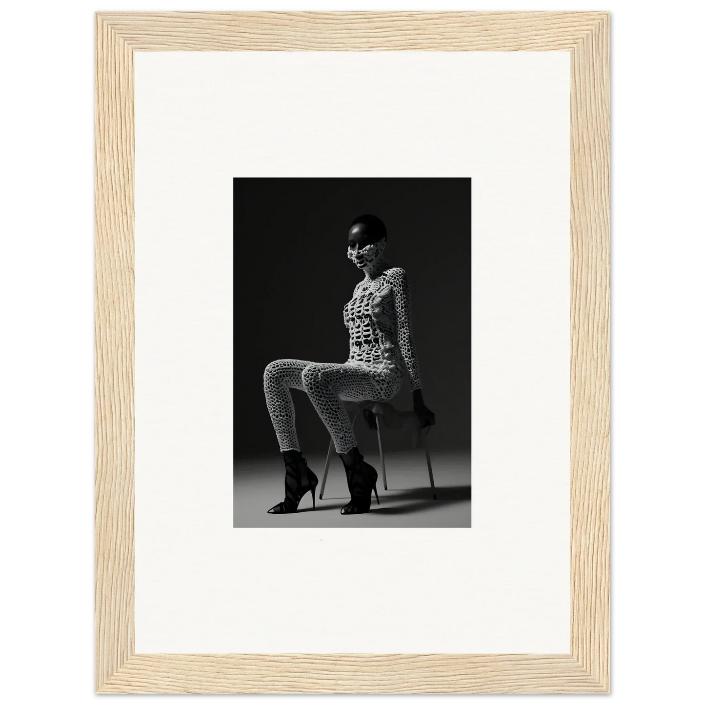 Black and white photograph of a seated woman in a patterned outfit and high heels.