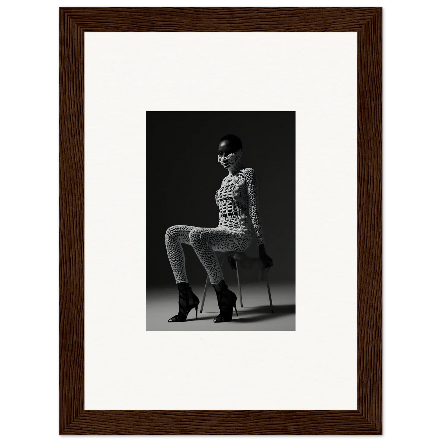 Black and white photograph of a seated woman in a patterned outfit and high heels.