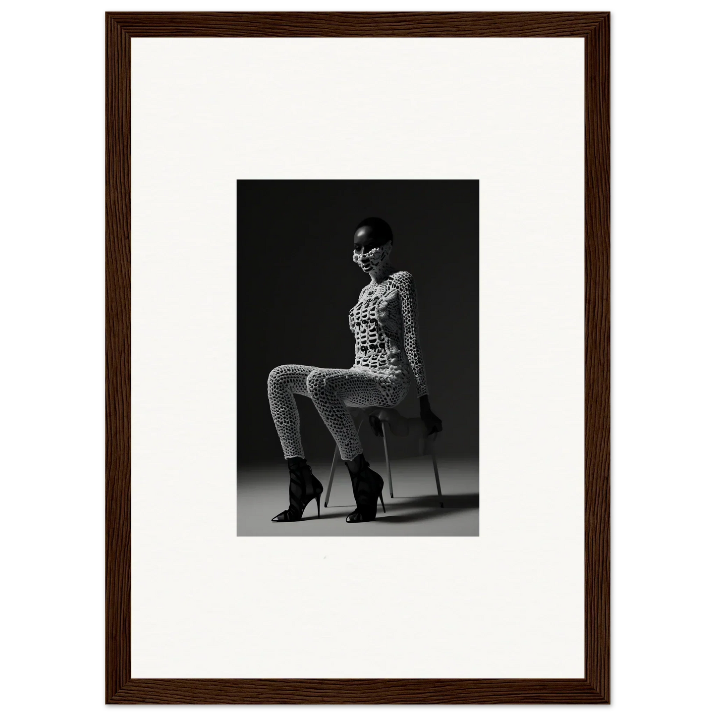 Black and white photograph of a woman seated on an invisible chair, wearing a patterned outfit and high heels.