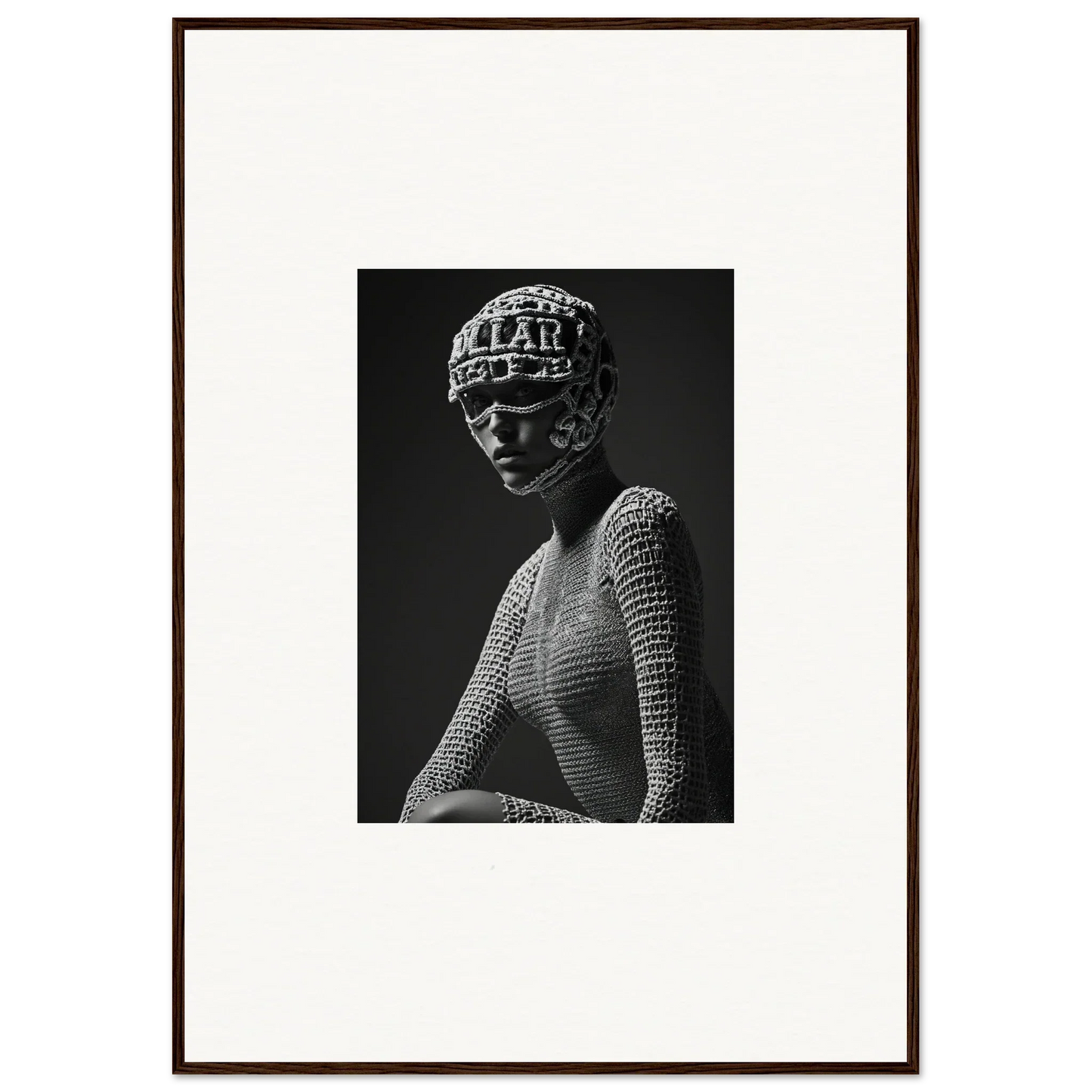 Black and white photograph of a figure wearing a patterned headpiece and textured top.