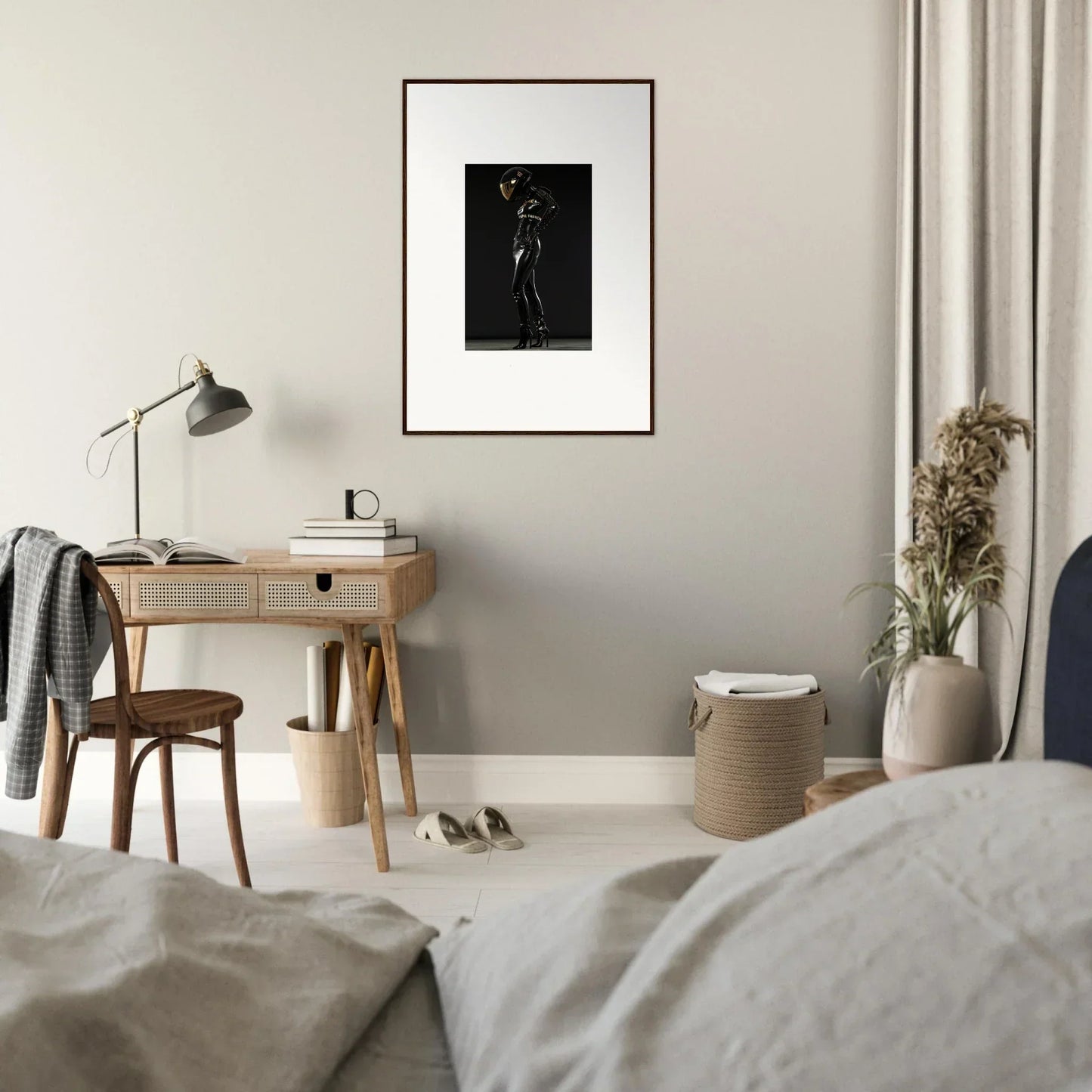 Minimalist bedroom featuring a wooden desk with a lamp and framed artwork above.