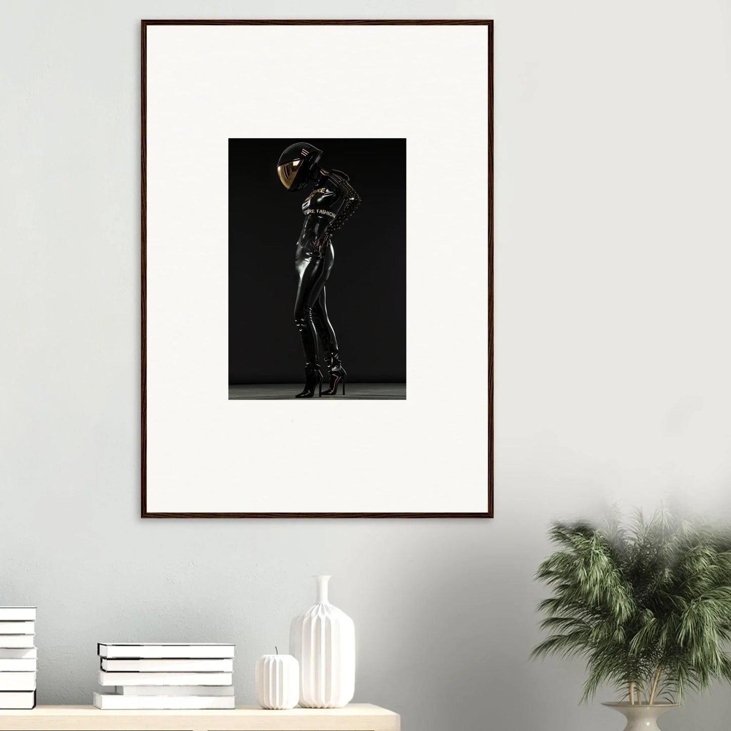 Framed photograph of a figure in a shiny black bodysuit striking a dramatic pose against a dark background.