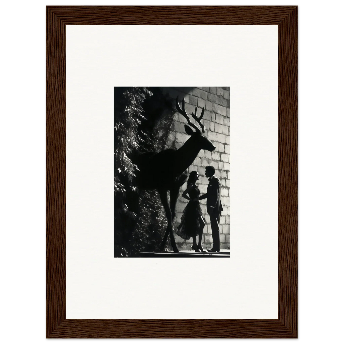 Framed black and white photograph showing silhouettes of a deer and two people against a wall.