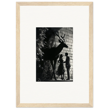 Framed black and white photograph showing silhouettes of a deer and two people against a brick wall.