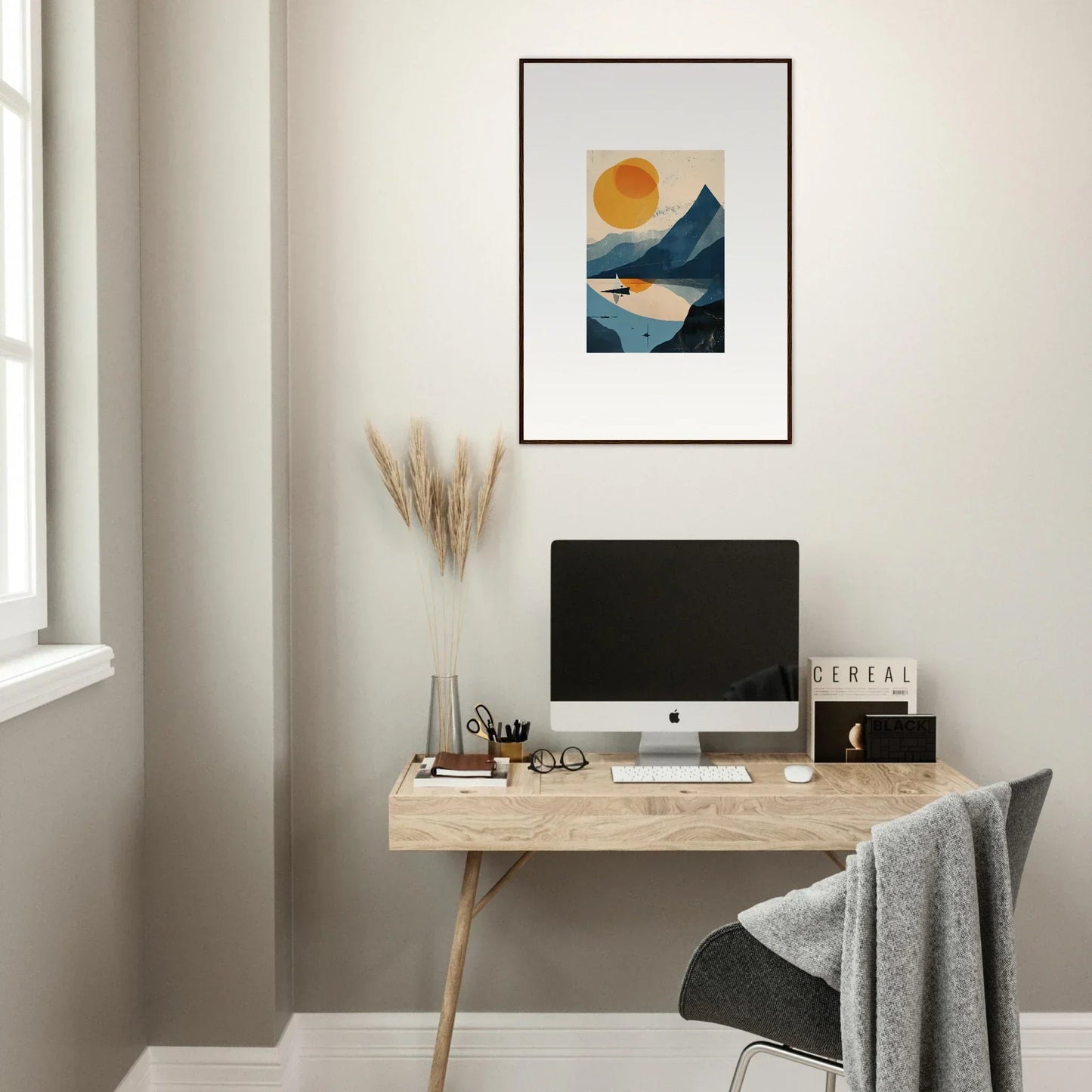 Minimalist home office workspace featuring a wooden desk, computer, and framed wall art