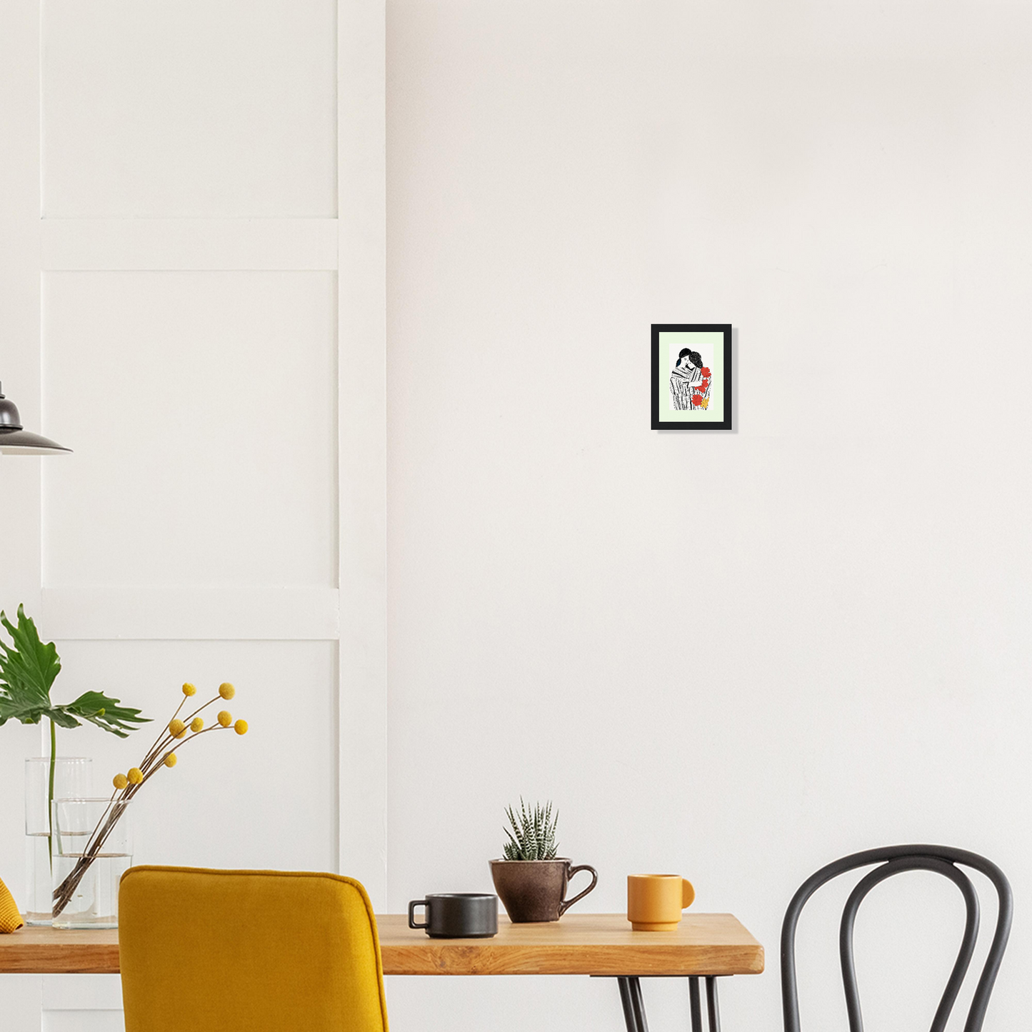 Minimalist dining area with a wooden table, yellow chair, and framed artwork on the wall.