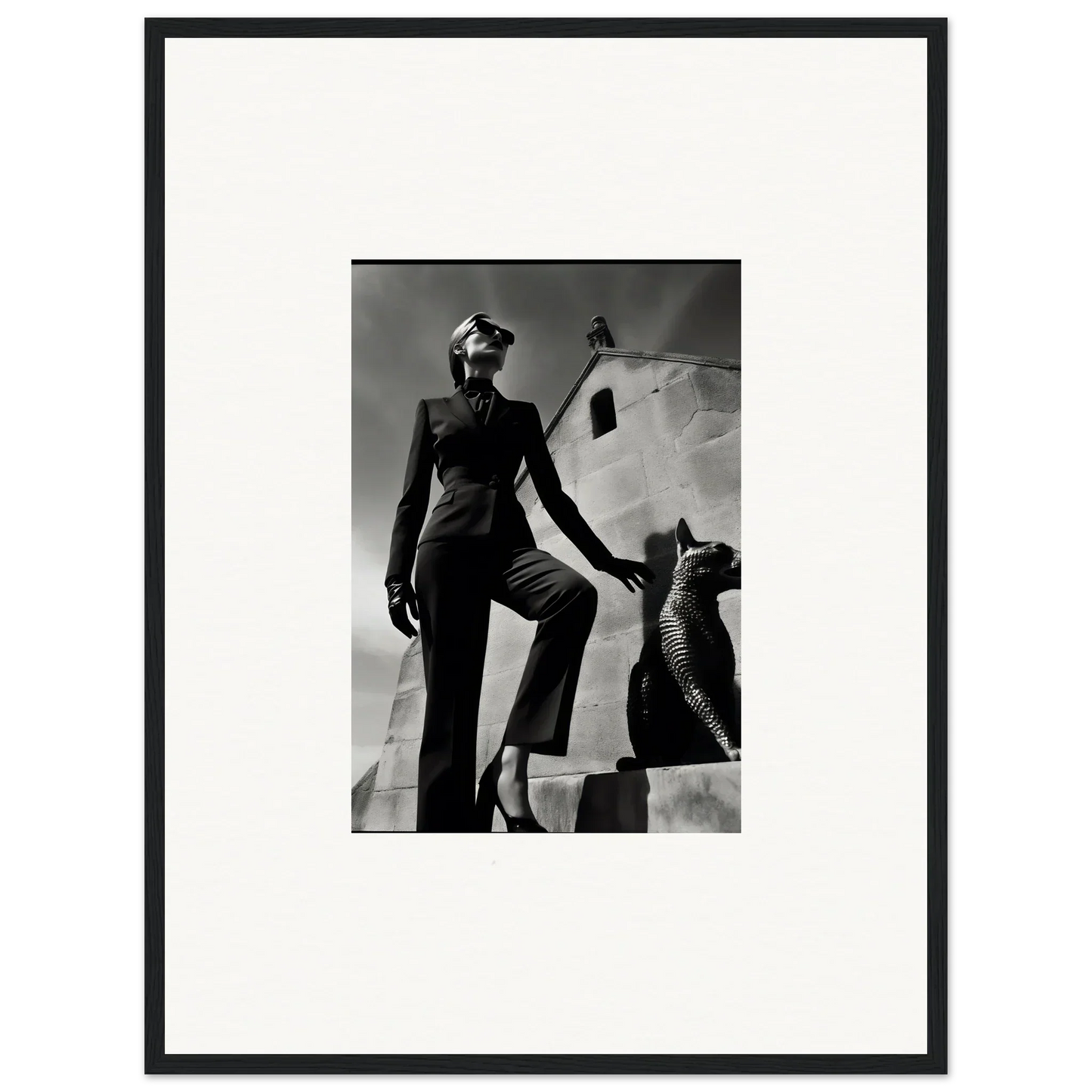 Black and white photograph of a woman in a tailored suit posing next to a sculptural form.