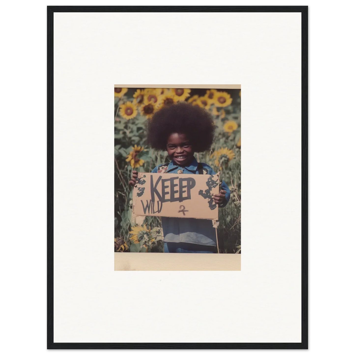 Framed photo of a person with a KEEP WILD sign in a sunflower field, perfect for room decoration