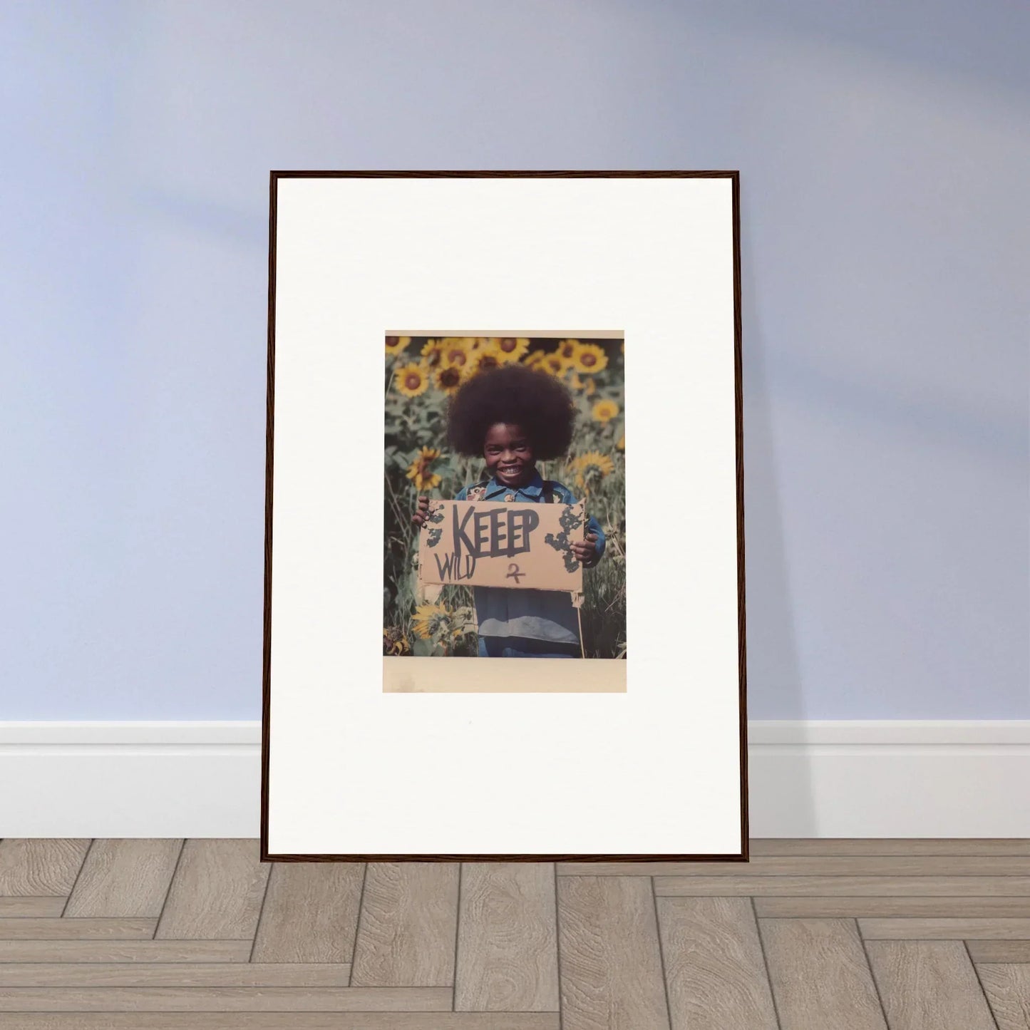 Framed canvas print of a person with an afro holding a KEEP sign in a sunflower field