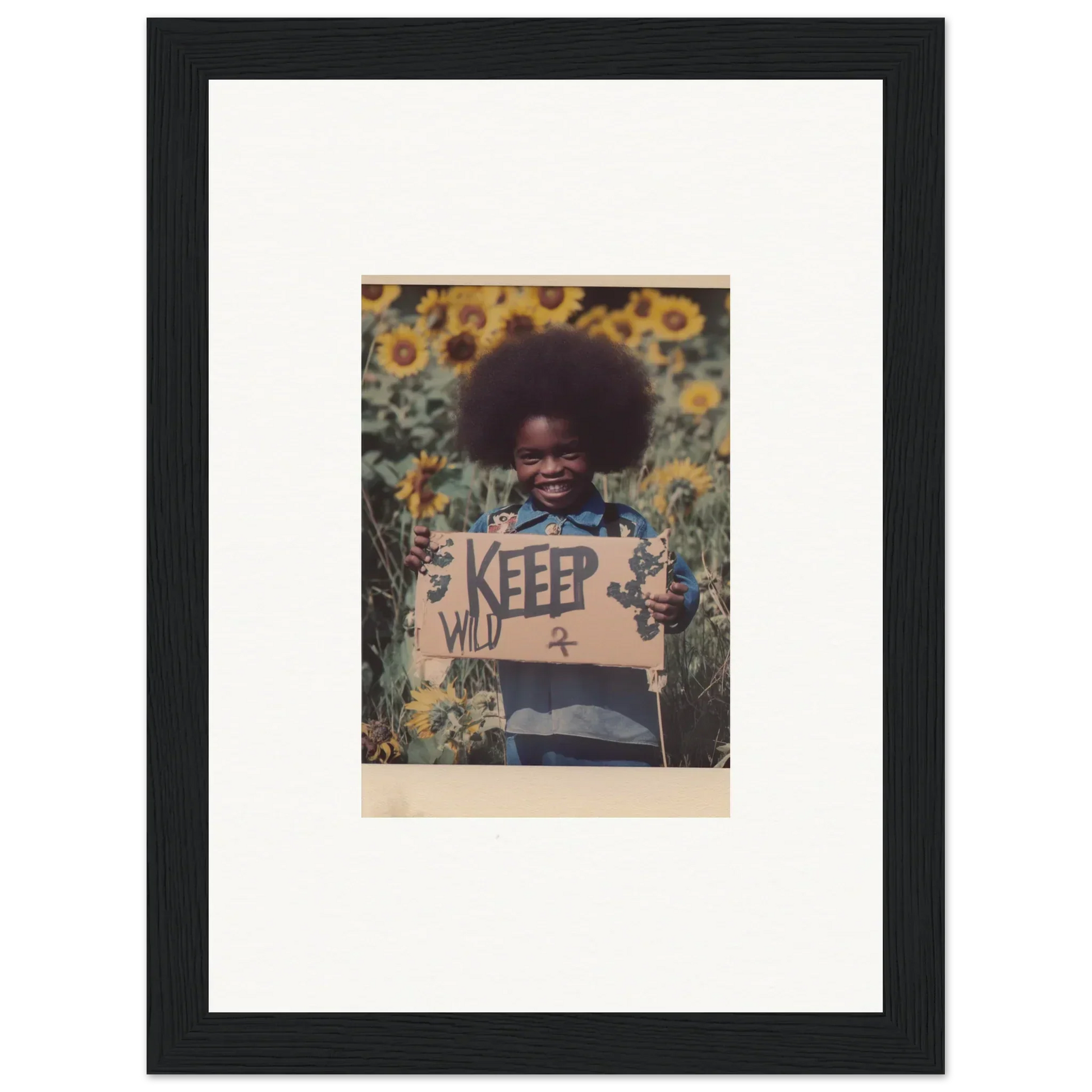 Framed photo of a person with an afro in sunflowers with a KEEP WILD sign for room decoration