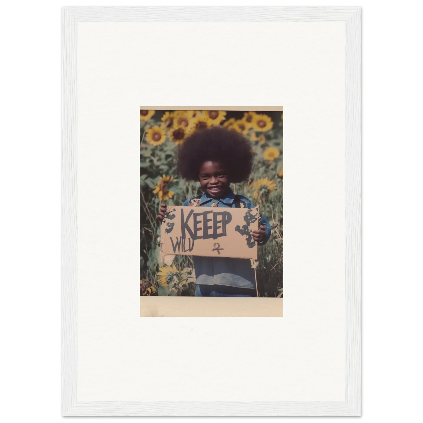 Framed photo of person with afro holding KEEP sign in a vibrant sunflower field for room decoration