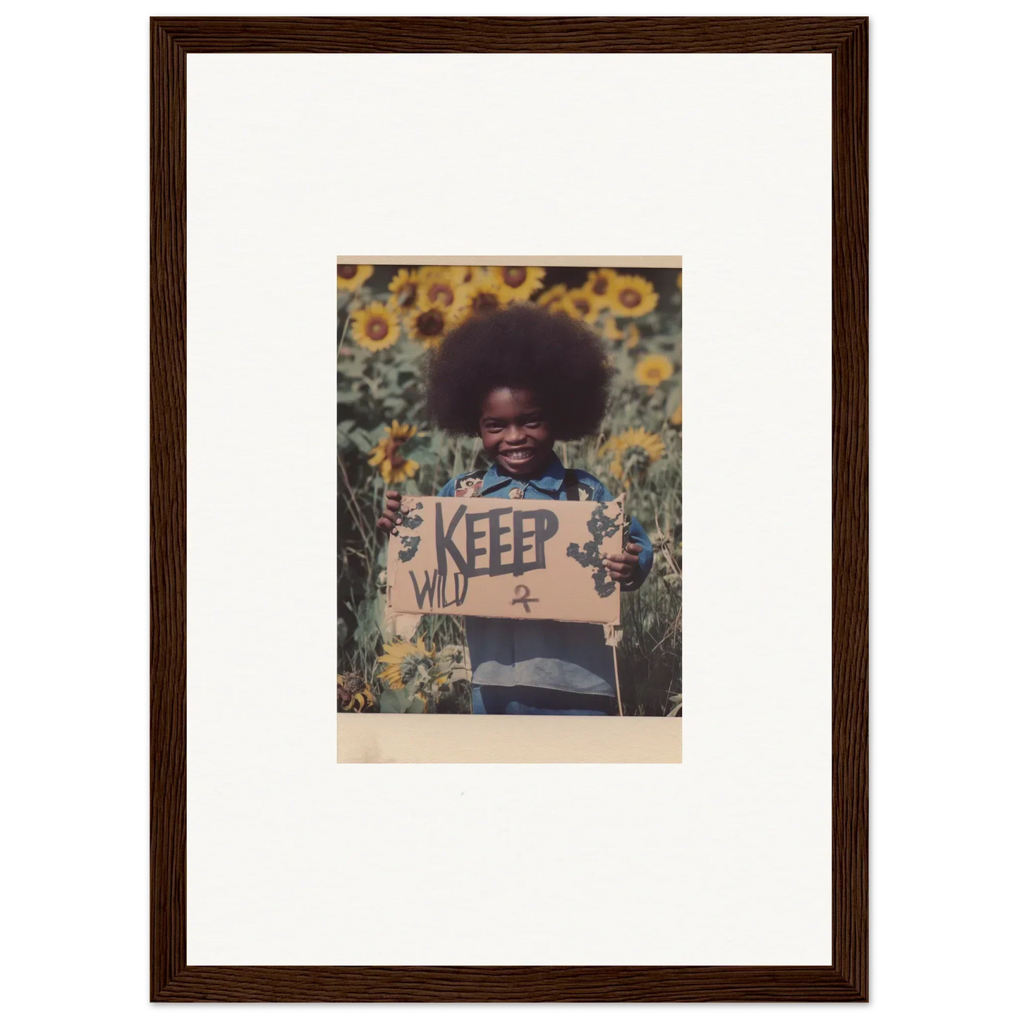 Framed canvas print of a person with an afro in sunflowers holding a KEEP WILD sign