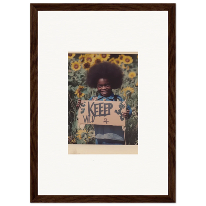 Framed canvas print of a person with an afro in sunflowers holding a KEEP WILD sign