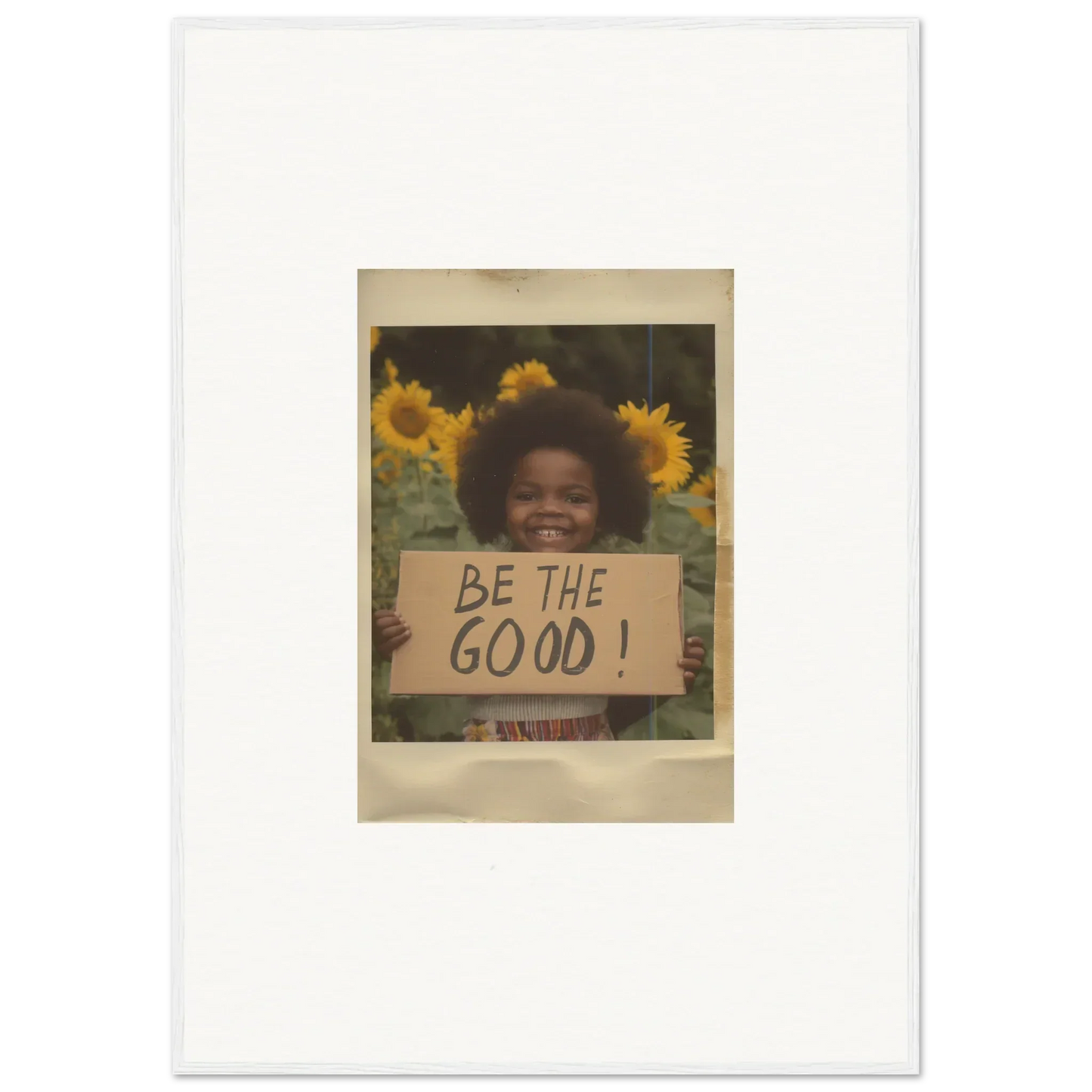 A vintage Polaroid of someone with a BE THE GOOD! sign in sunflowers, perfect for Sunflower Utopia Surge framed wall art