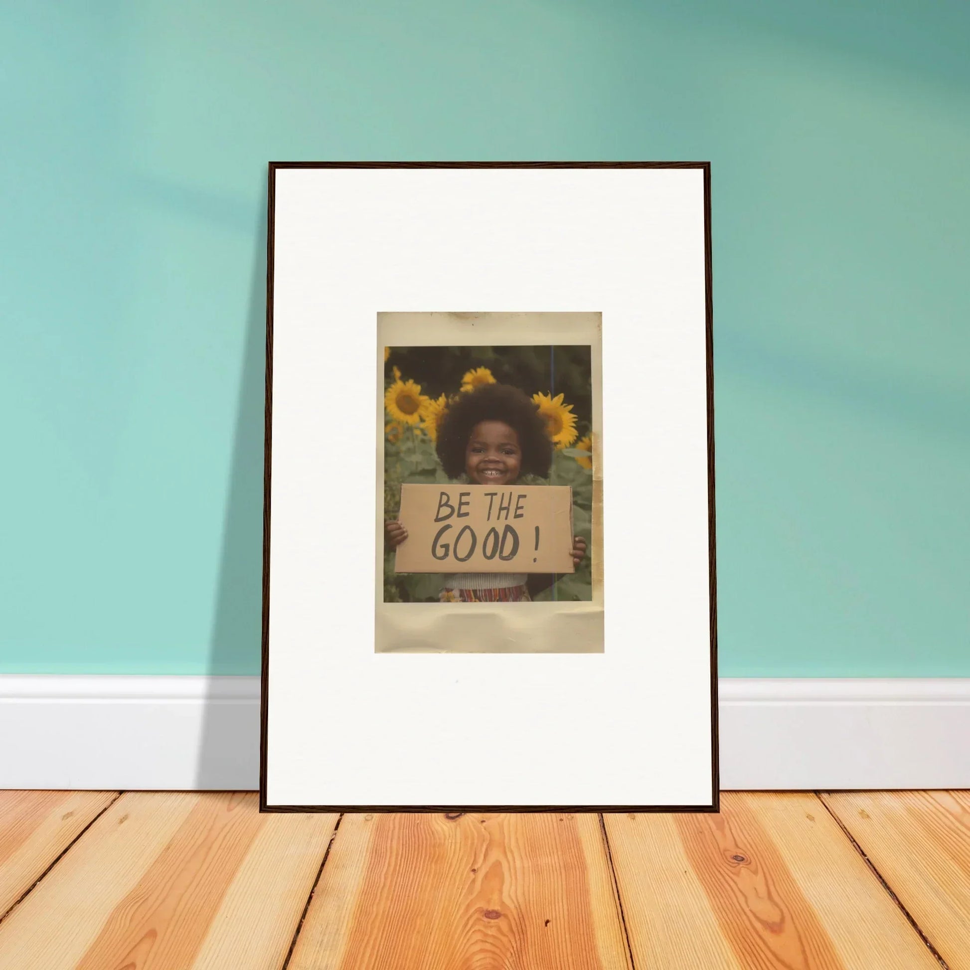 Framed wall art featuring a person holding a sign that says BE THE GOOD in Sunflower Utopia Surge